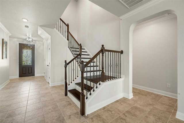 tiled foyer entrance with ornamental molding and a textured ceiling