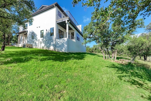 view of side of property featuring a balcony and a lawn