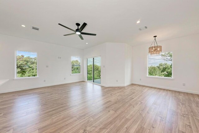 empty room with light wood-type flooring and ceiling fan with notable chandelier