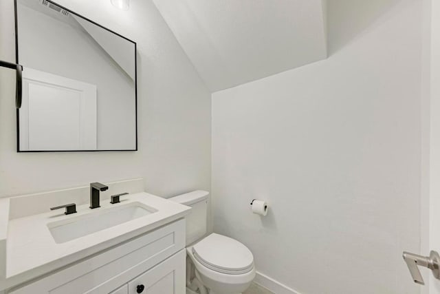 bathroom featuring vanity, lofted ceiling, and toilet