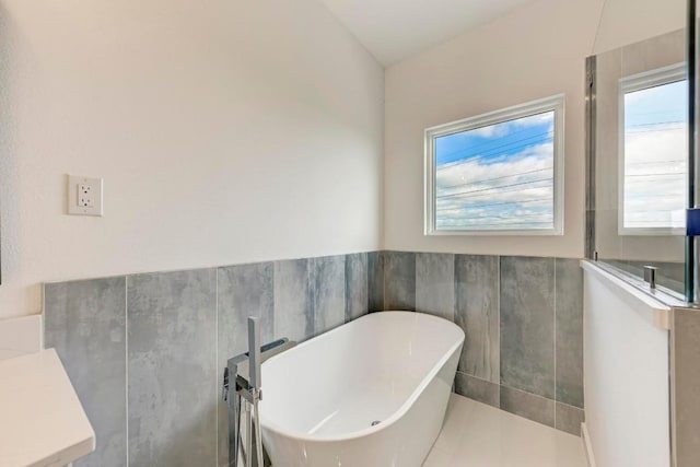 bathroom with tile walls, a tub to relax in, and a wealth of natural light