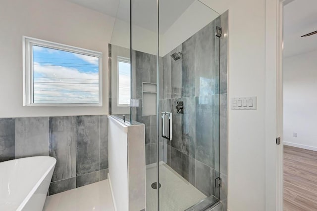 bathroom featuring wood-type flooring and shower with separate bathtub