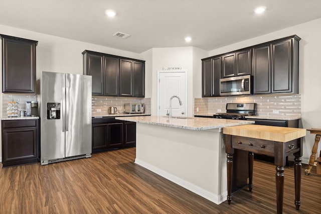 kitchen featuring sink, dark brown cabinets, dark hardwood / wood-style floors, an island with sink, and stainless steel appliances