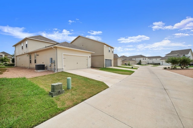 view of side of home with a garage, a yard, and central AC