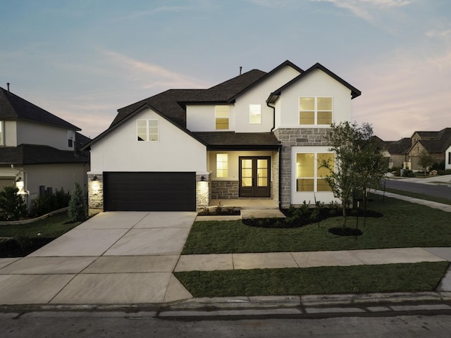 view of front of home featuring french doors, a garage, and a lawn