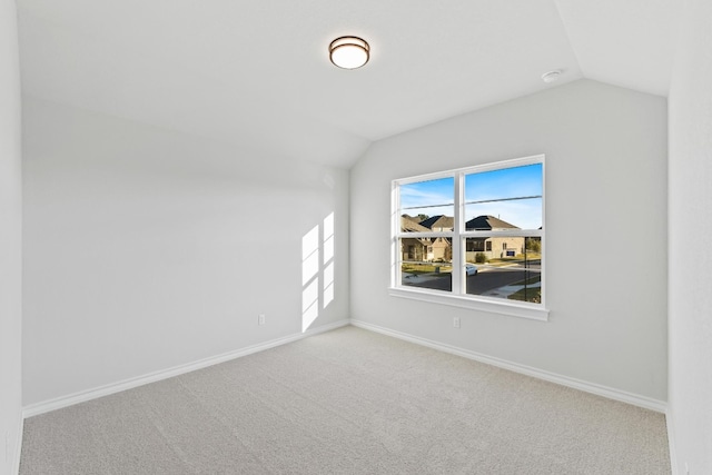 carpeted empty room with vaulted ceiling