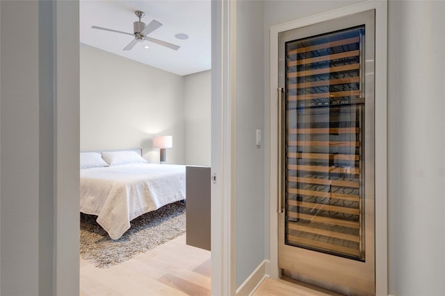 bedroom featuring ceiling fan, beverage cooler, and light wood-type flooring