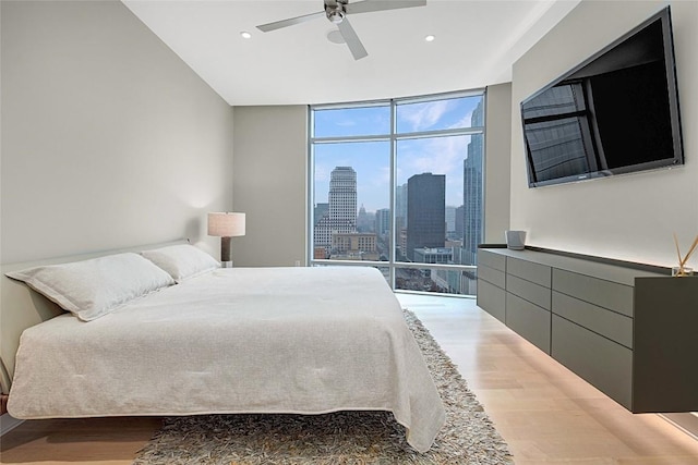 bedroom with expansive windows, ceiling fan, and light wood-type flooring