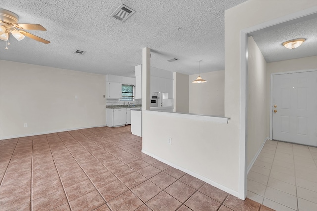 interior space with light tile patterned flooring, a textured ceiling, and ceiling fan