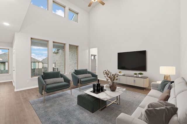 living room featuring a high ceiling, ceiling fan, and hardwood / wood-style floors