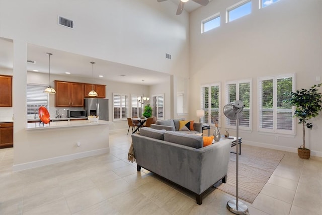 15008 Via Del Corso Dr, Bee Cave, TX 78738 - living room with a towering ceiling, ceiling fan, light tile patterned floors, a chandelier, and baseboards