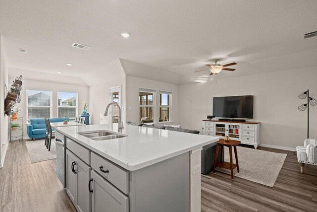 kitchen featuring gray cabinetry, hardwood / wood-style floors, sink, an island with sink, and ceiling fan