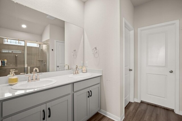 bathroom with double vanity, wood-type flooring, and walk in shower