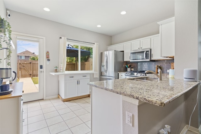 kitchen with white cabinets, stainless steel appliances, backsplash, and a wealth of natural light