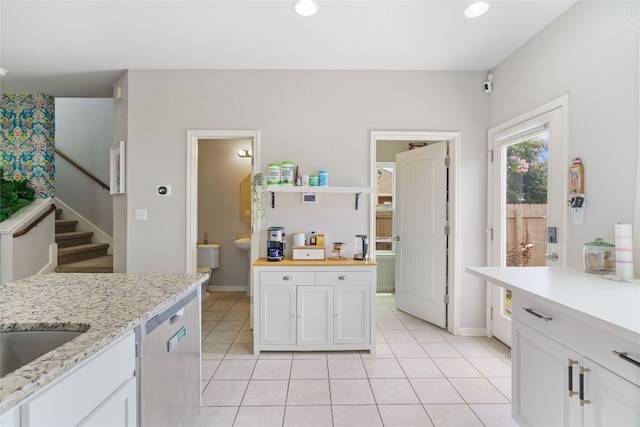 kitchen with light tile patterned flooring, dishwasher, butcher block countertops, and white cabinets