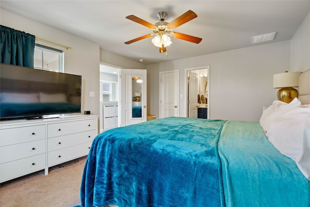 bedroom with ensuite bath, light carpet, and ceiling fan