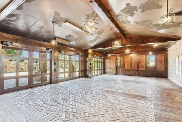 interior space featuring light wood-style floors, wood walls, and lofted ceiling with beams