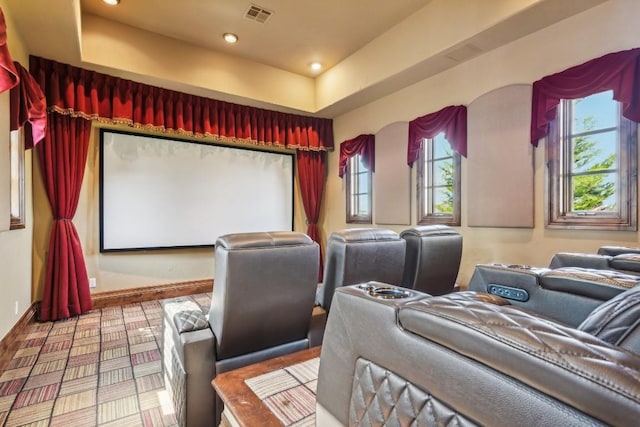 home theater room featuring baseboards, a raised ceiling, visible vents, and recessed lighting