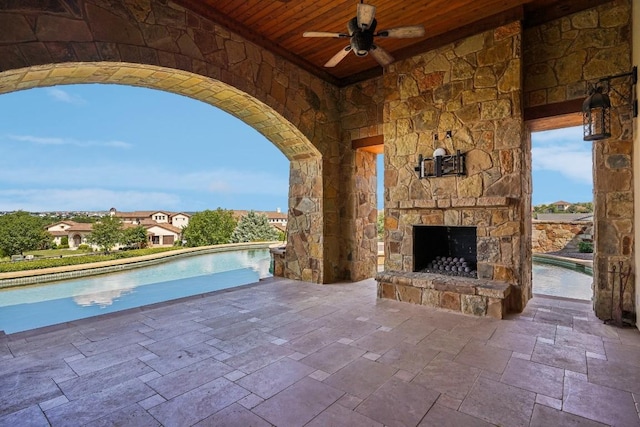 view of patio featuring a ceiling fan, an outdoor pool, and an outdoor stone fireplace