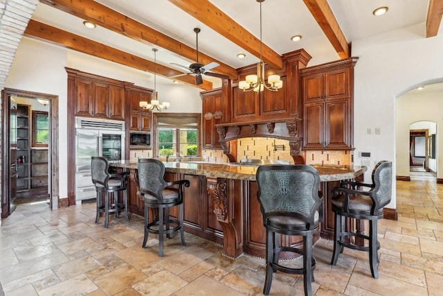 226 Canyon Turn Trl, Austin, TX 78734 - kitchen featuring a chandelier, stone tile floors, built in appliances, arched walkways, and decorative backsplash