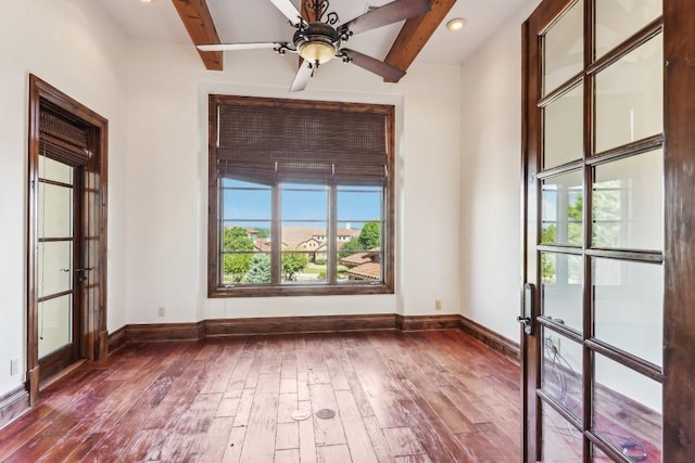 empty room featuring baseboards, french doors, wood finished floors, and beam ceiling