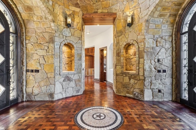 foyer with arched walkways and dark wood-type flooring