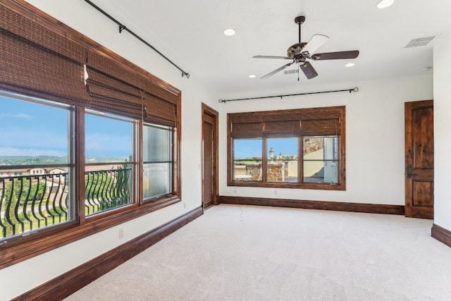 empty room with baseboards, visible vents, and light carpet