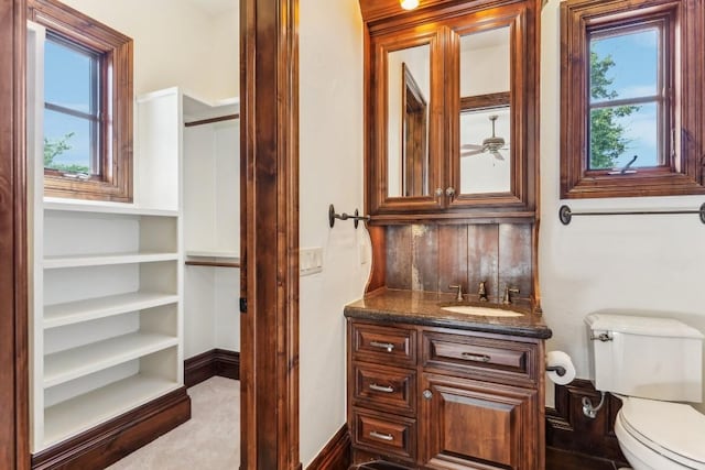 bathroom with vanity, toilet, ceiling fan, and baseboards