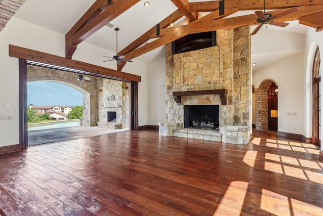 unfurnished living room featuring wood finished floors, a ceiling fan, high vaulted ceiling, a fireplace, and beamed ceiling