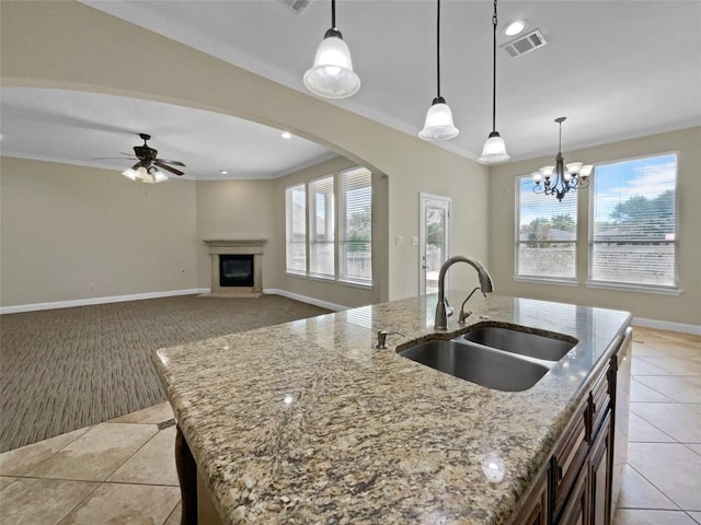 kitchen with decorative light fixtures, a kitchen island with sink, and sink