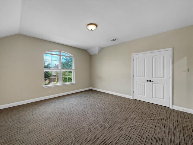 carpeted empty room featuring vaulted ceiling