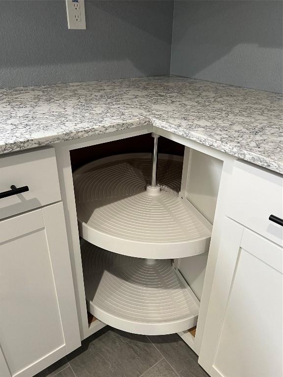 room details featuring dark tile patterned floors, white cabinetry, and light stone counters