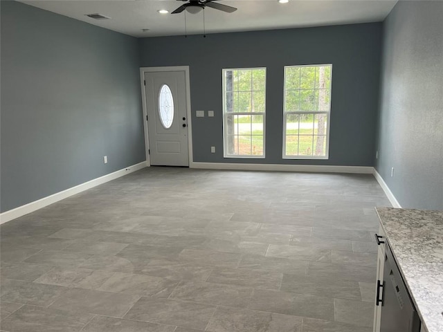 interior space featuring baseboards, a ceiling fan, visible vents, and a healthy amount of sunlight