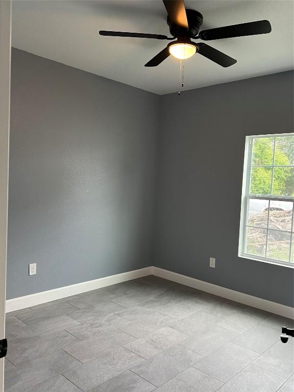 unfurnished room featuring a ceiling fan and baseboards