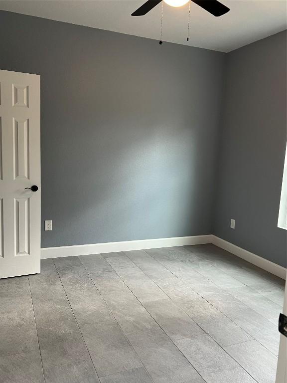 spare room with ceiling fan and baseboards