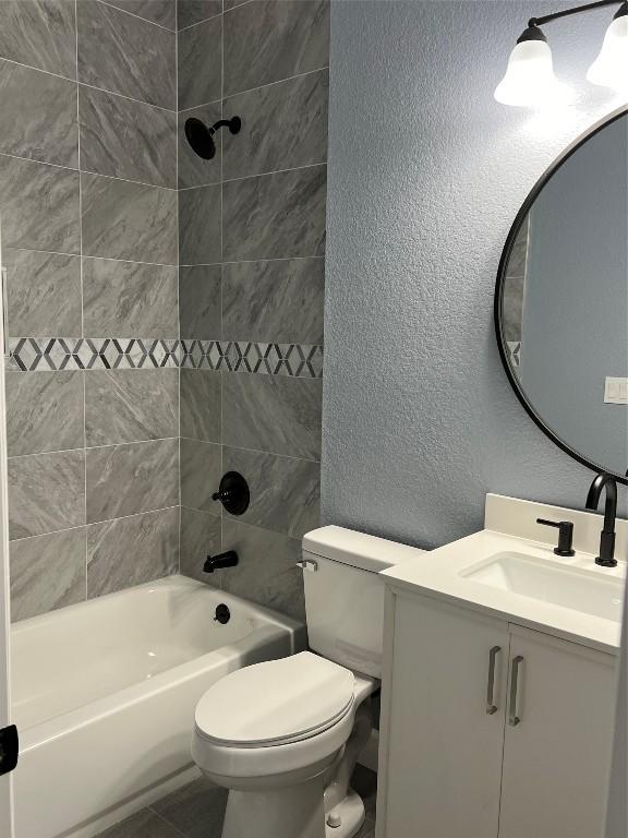 full bath featuring bathing tub / shower combination, a textured wall, toilet, vanity, and tile patterned flooring