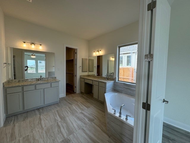 bathroom featuring vanity and tiled bath