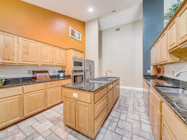 kitchen with sink, light brown cabinetry, an island with sink, and appliances with stainless steel finishes