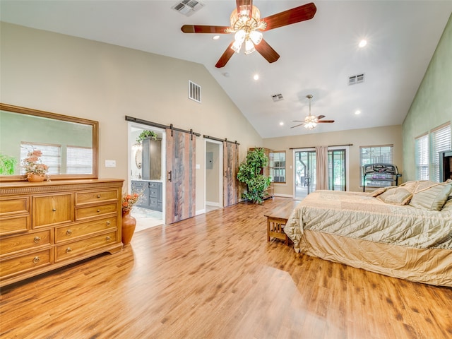 bedroom with connected bathroom, high vaulted ceiling, light wood-type flooring, a barn door, and ceiling fan