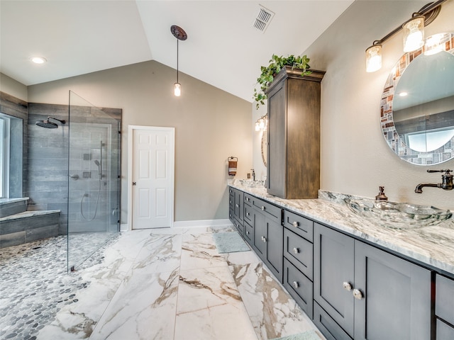 bathroom with a tile shower, vaulted ceiling, and vanity