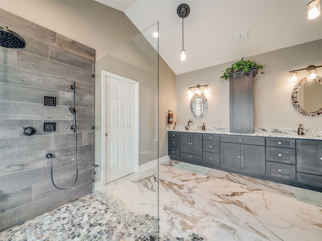 bathroom with tiled shower, lofted ceiling, and vanity