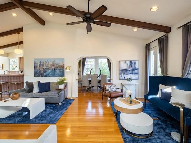 living room featuring beam ceiling, hardwood / wood-style flooring, high vaulted ceiling, and ceiling fan