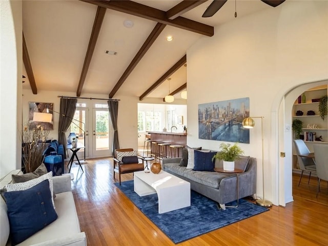 living room featuring beamed ceiling, wood-type flooring, high vaulted ceiling, and ceiling fan