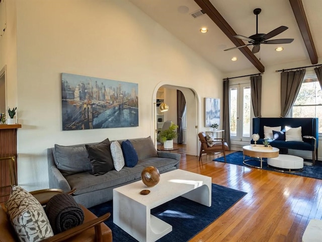 living room featuring beamed ceiling, wood-type flooring, high vaulted ceiling, and ceiling fan