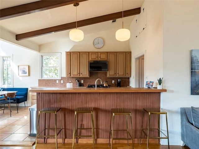 kitchen with black microwave, kitchen peninsula, hanging light fixtures, and a breakfast bar