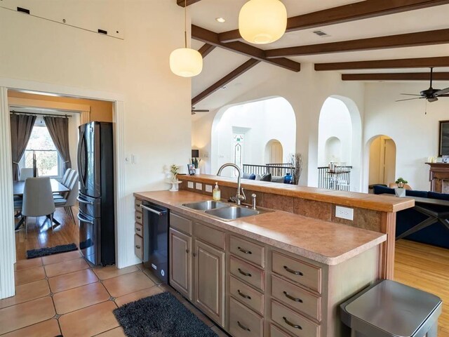 kitchen with light hardwood / wood-style flooring, ceiling fan, black appliances, lofted ceiling with beams, and sink