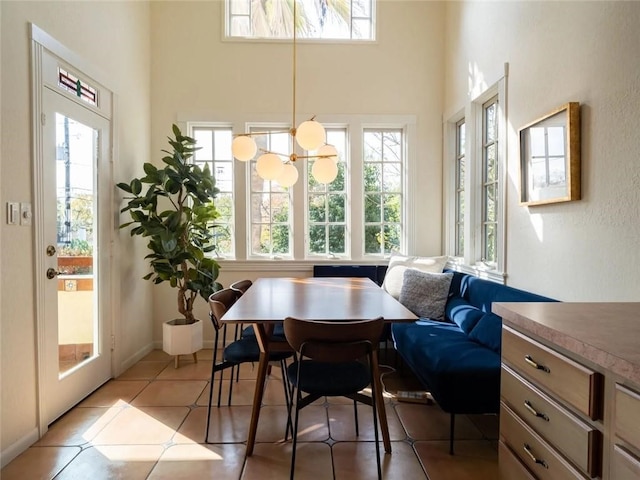 tiled dining room featuring a high ceiling, a notable chandelier, and a wealth of natural light