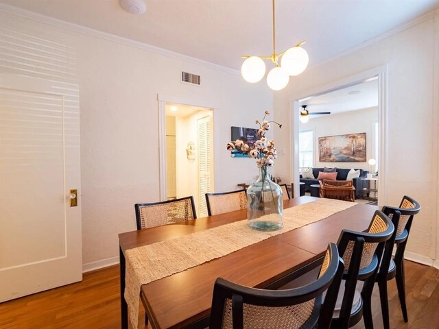 dining area featuring crown molding, ceiling fan with notable chandelier, and wood-type flooring