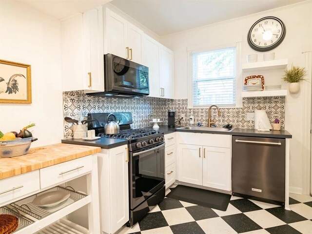 kitchen with tasteful backsplash, stainless steel appliances, sink, wood counters, and dark tile patterned flooring