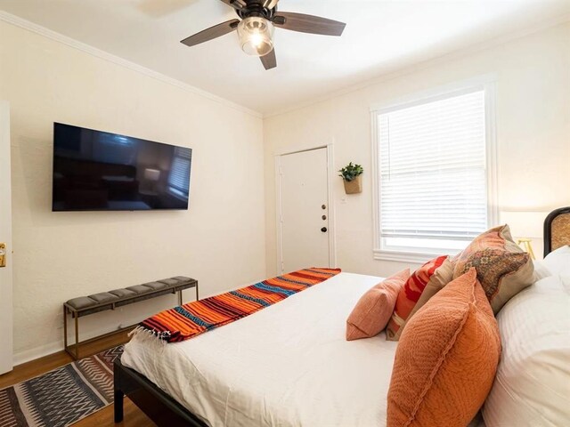 bedroom with hardwood / wood-style flooring, crown molding, and ceiling fan